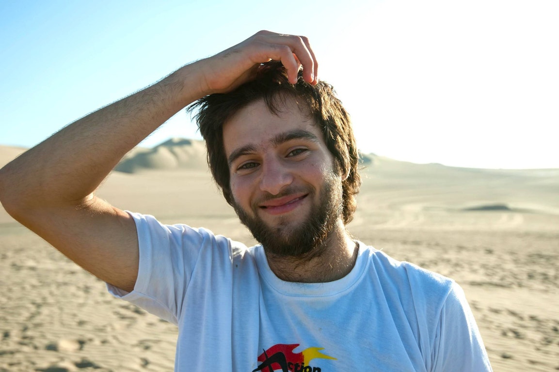Gap year for mental health: smiling young man standing in the desert under clear blue skies