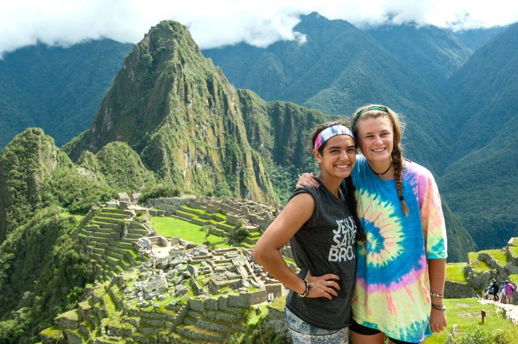 Two friends smile in front of Machu Picchu in Peru during a young adult group travel program.