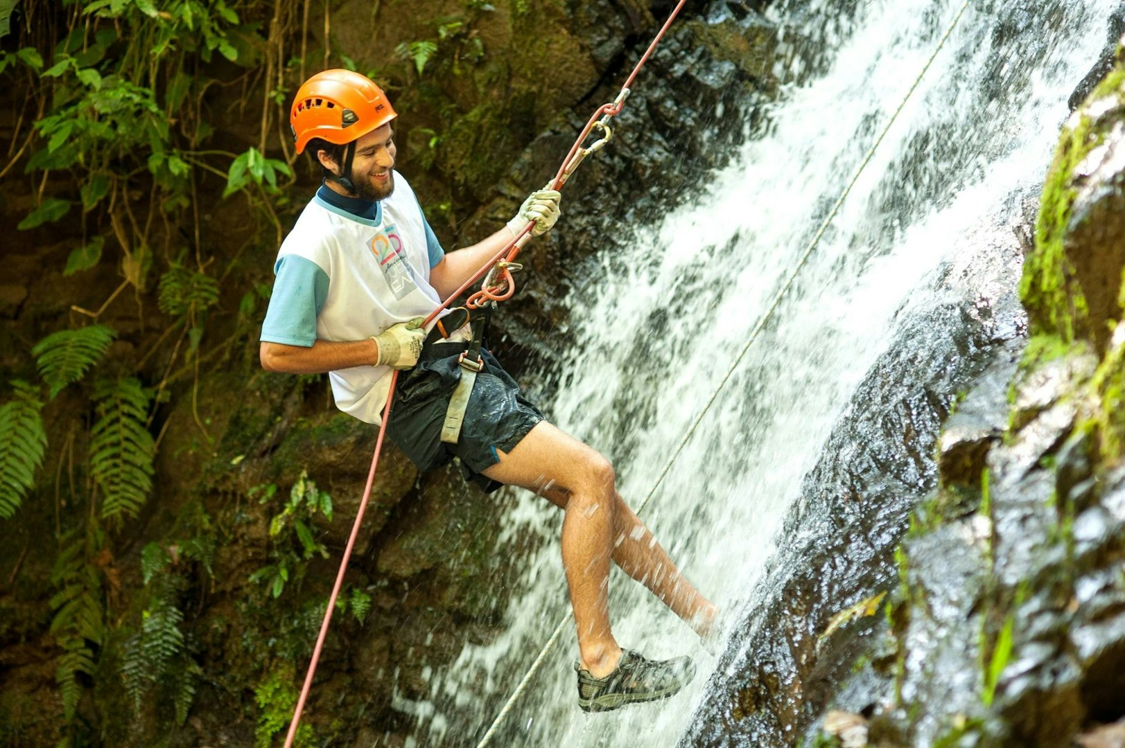 Gap year student rappelling down a waterfall on an outdoor adventure.