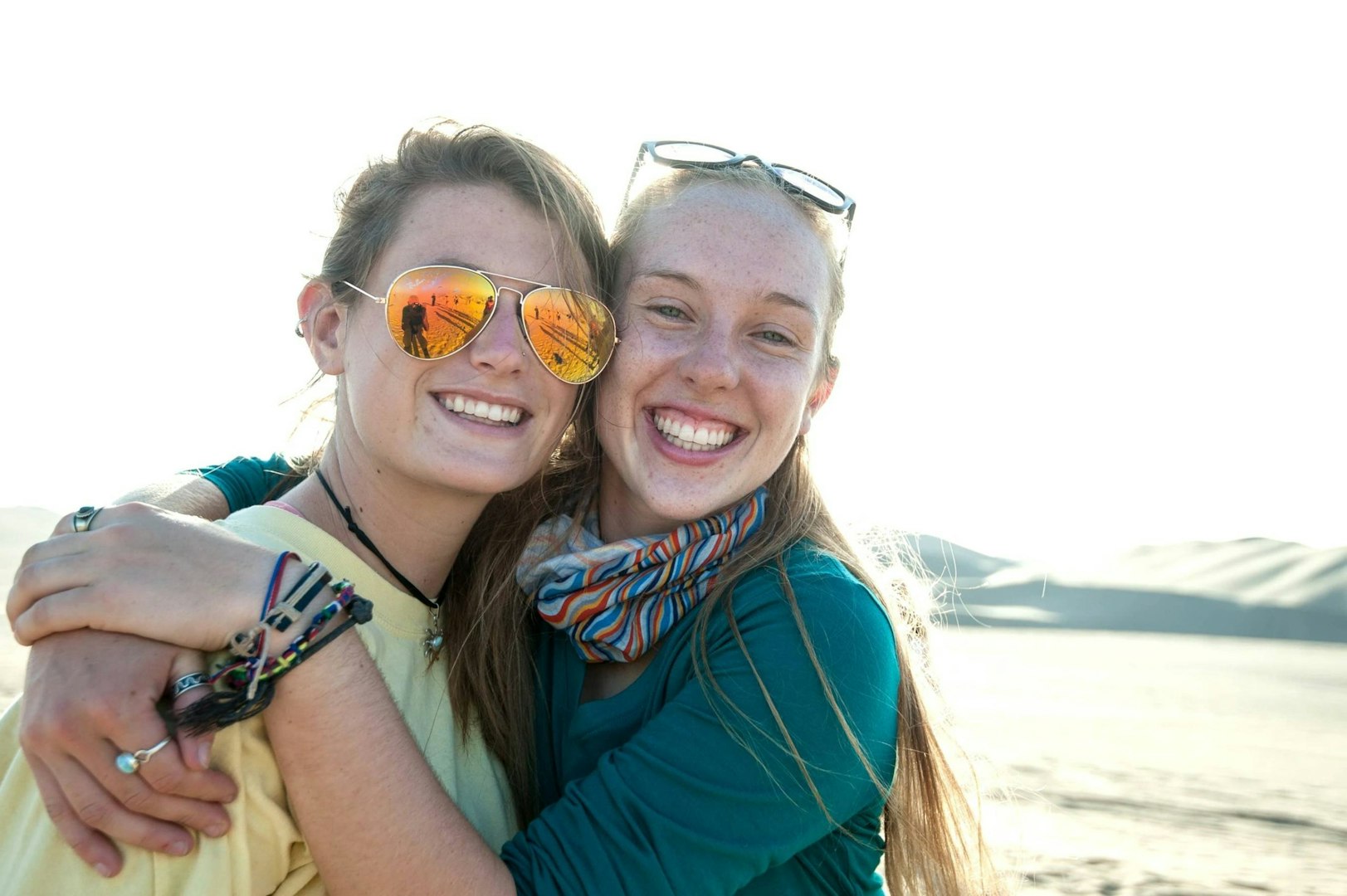 Two gap year students smiling and hugging during their travel abroad.