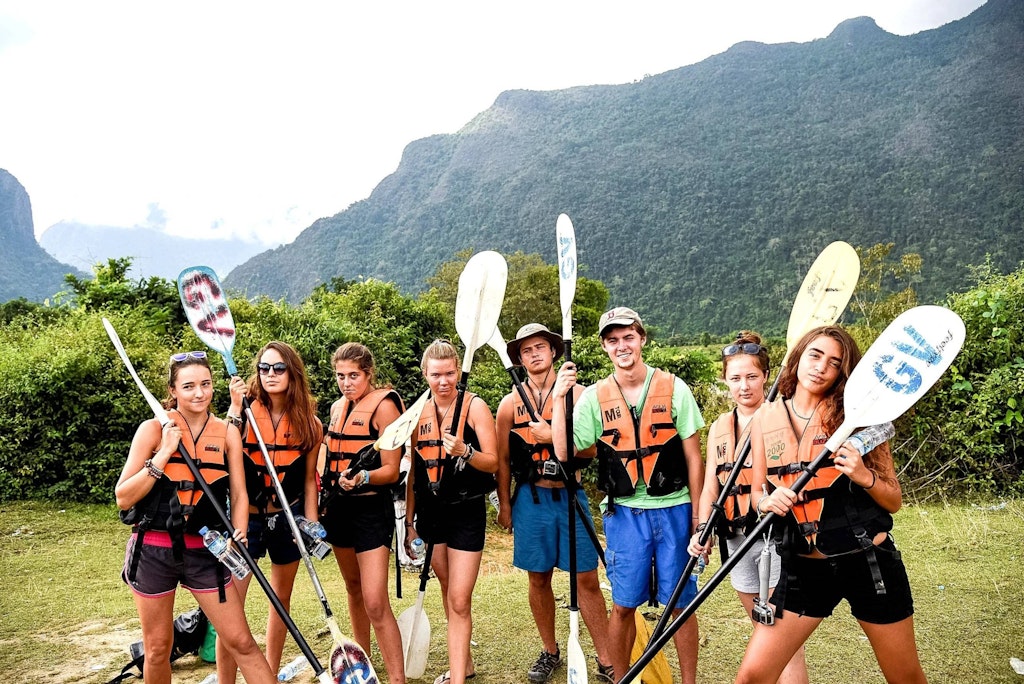 Gap year vs college: students preparing for a group kayaking adventure during their gap year.