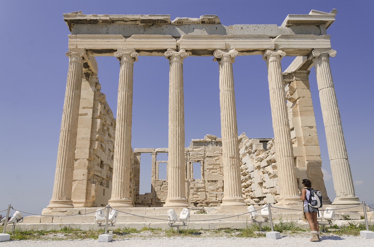 A student pauses beneath the towering columns of an ancient Greek temple