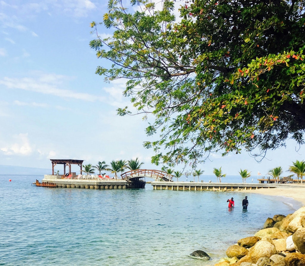 Photo of Moulin Sur Mer Beach Resort in Haiti with bridge over ocean and place to sit and enjoy ocean view.