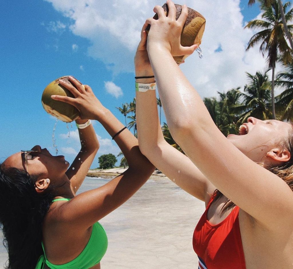 Two teens drinking from coconut shells during a teen travel program