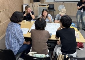 High School Travel Opportunities in Korea - A group of students leading an educational discussion with local community members in South Korea. With a teen travel documents guide on the table
