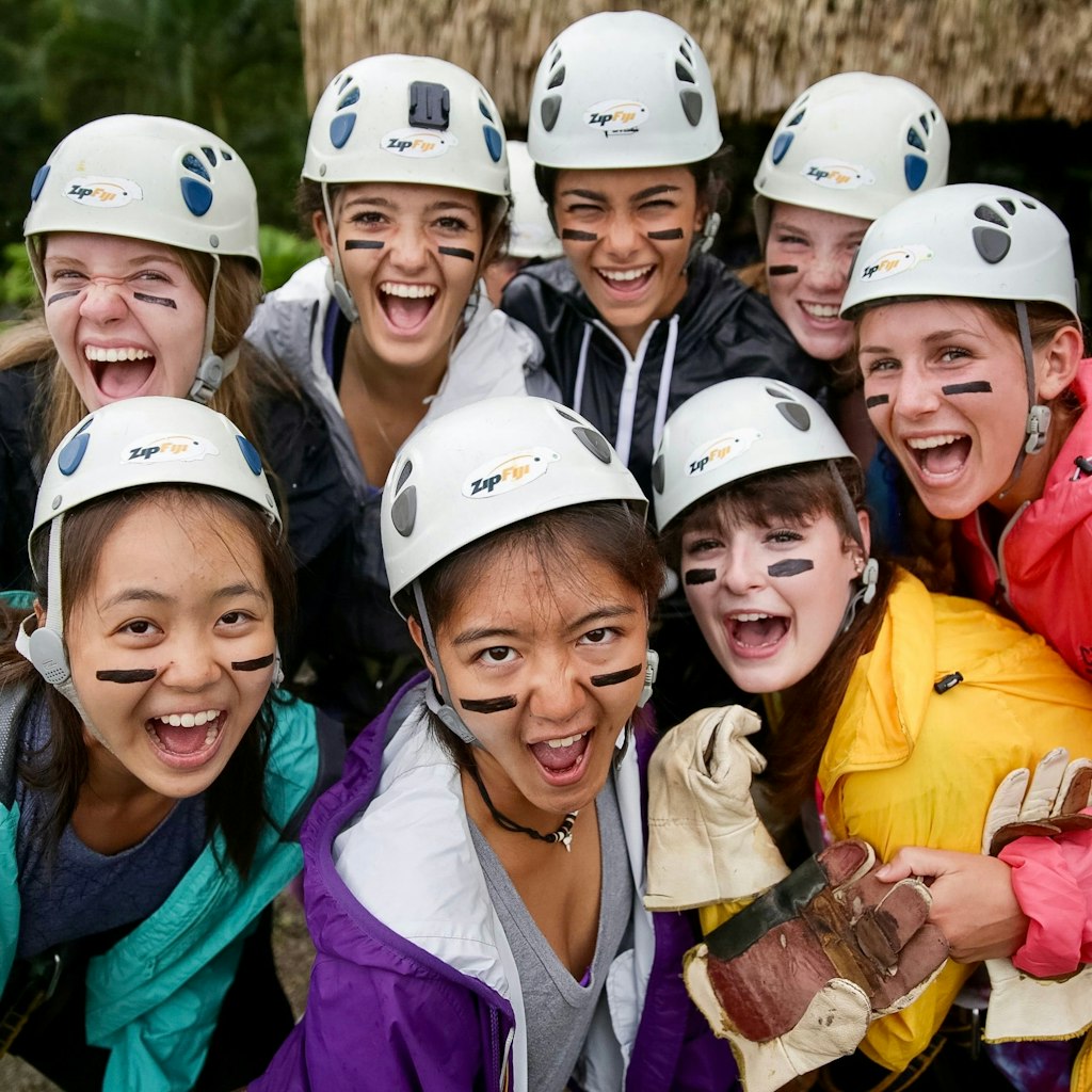 How to plan a teen travel. Summer Travel Programs for High School Students. High School Students on a summer travel program smiling and wearing helmets getting ready to for an outdoor activity.