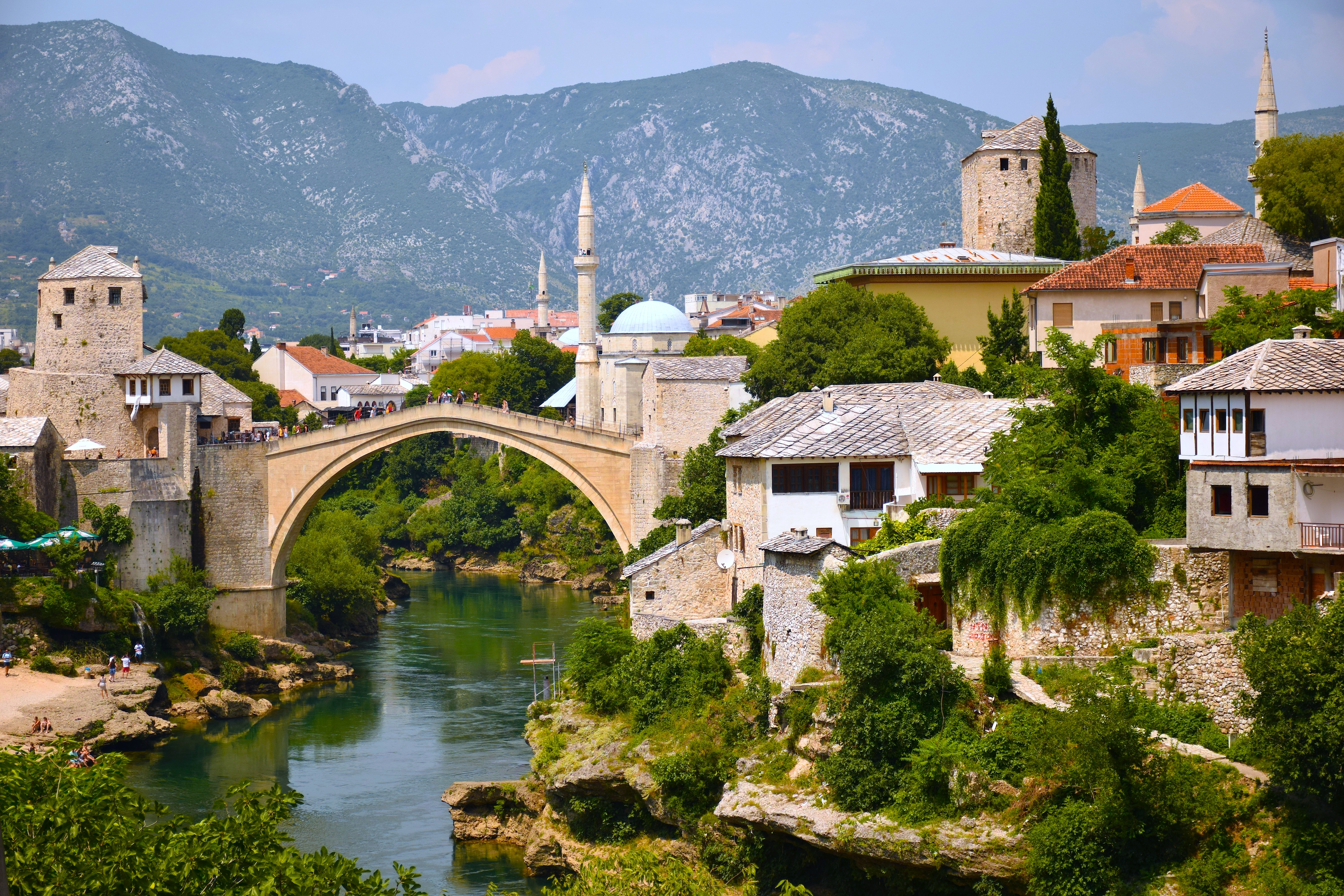 Stari Most bridge arches over a river below a hillside town in Mostar