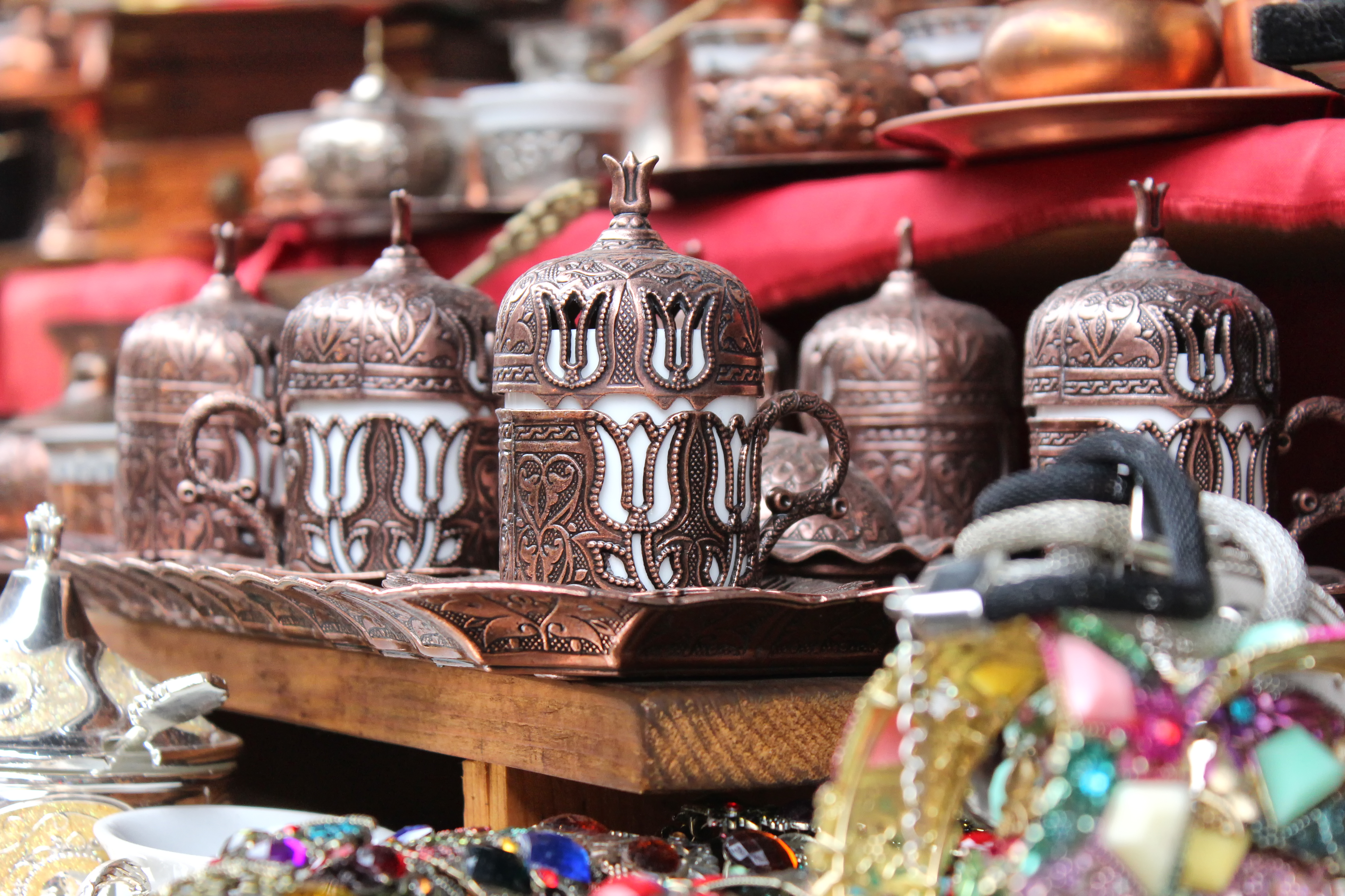 Students browse a market stall displaying ornate copper coffee pots with tulip designs