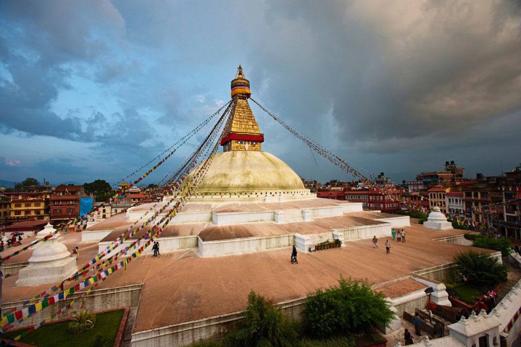 Boudhanath Stupa's golden spire and prayer flags rise above Kathmandu's rooftops at dusk