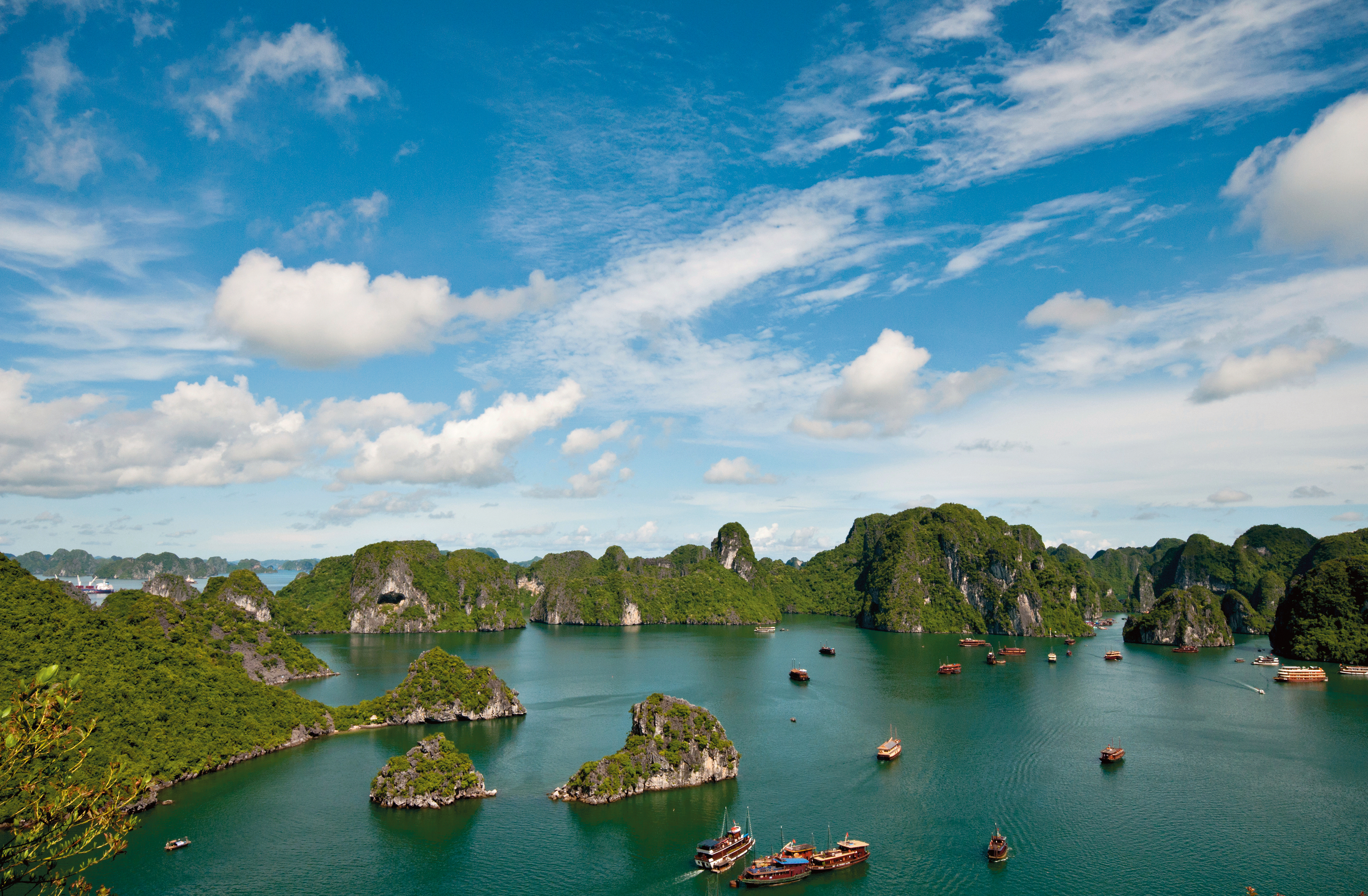 Scenic view of Ha Long Bay in Vietnam with limestone islands and boats under a bright blue sky.