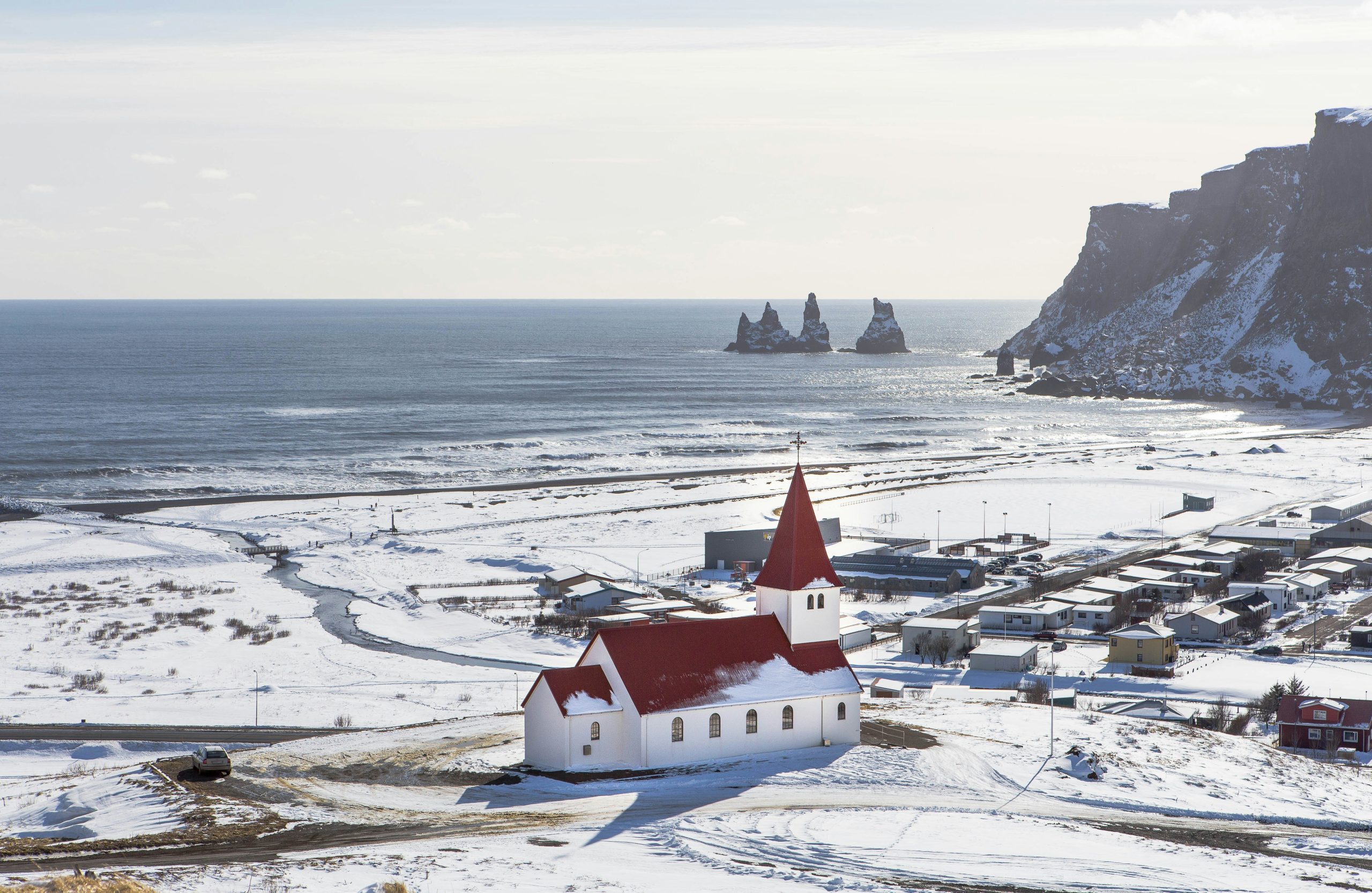 Picture of Vik in Iceland with snowy village and ocean and mountains in the background.