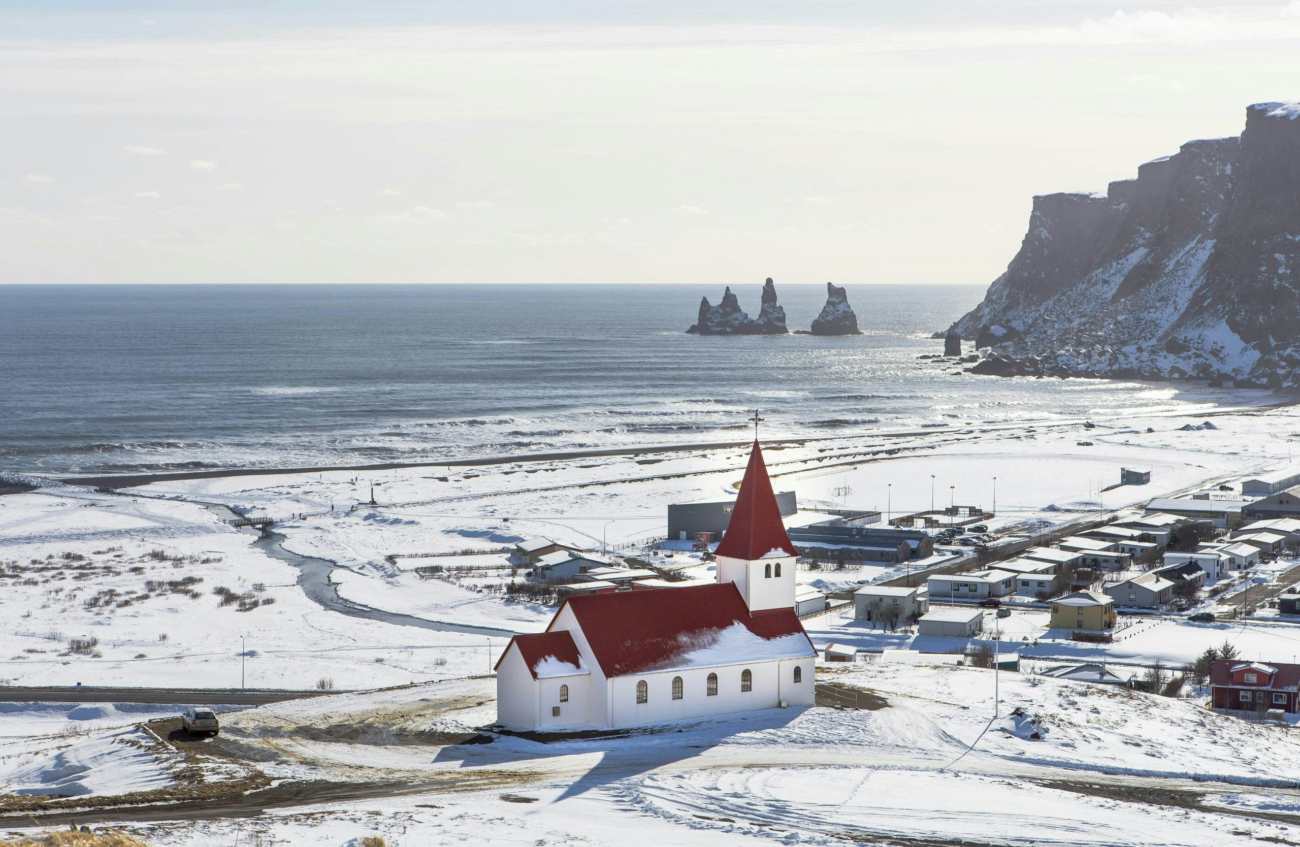 Picture of Vik in Iceland with snowy village and ocean and mountains in the background.