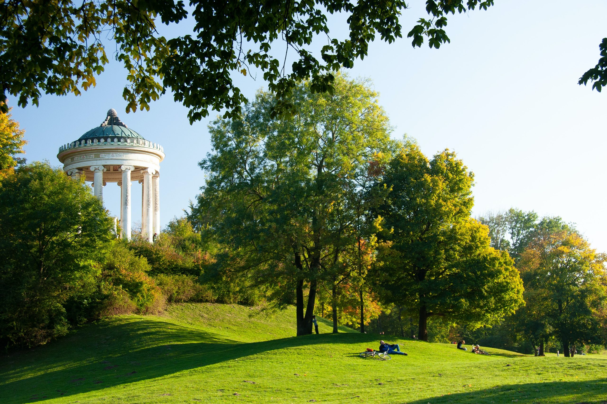 A domed pavilion overlooks a grassy park where students relax on the lawn