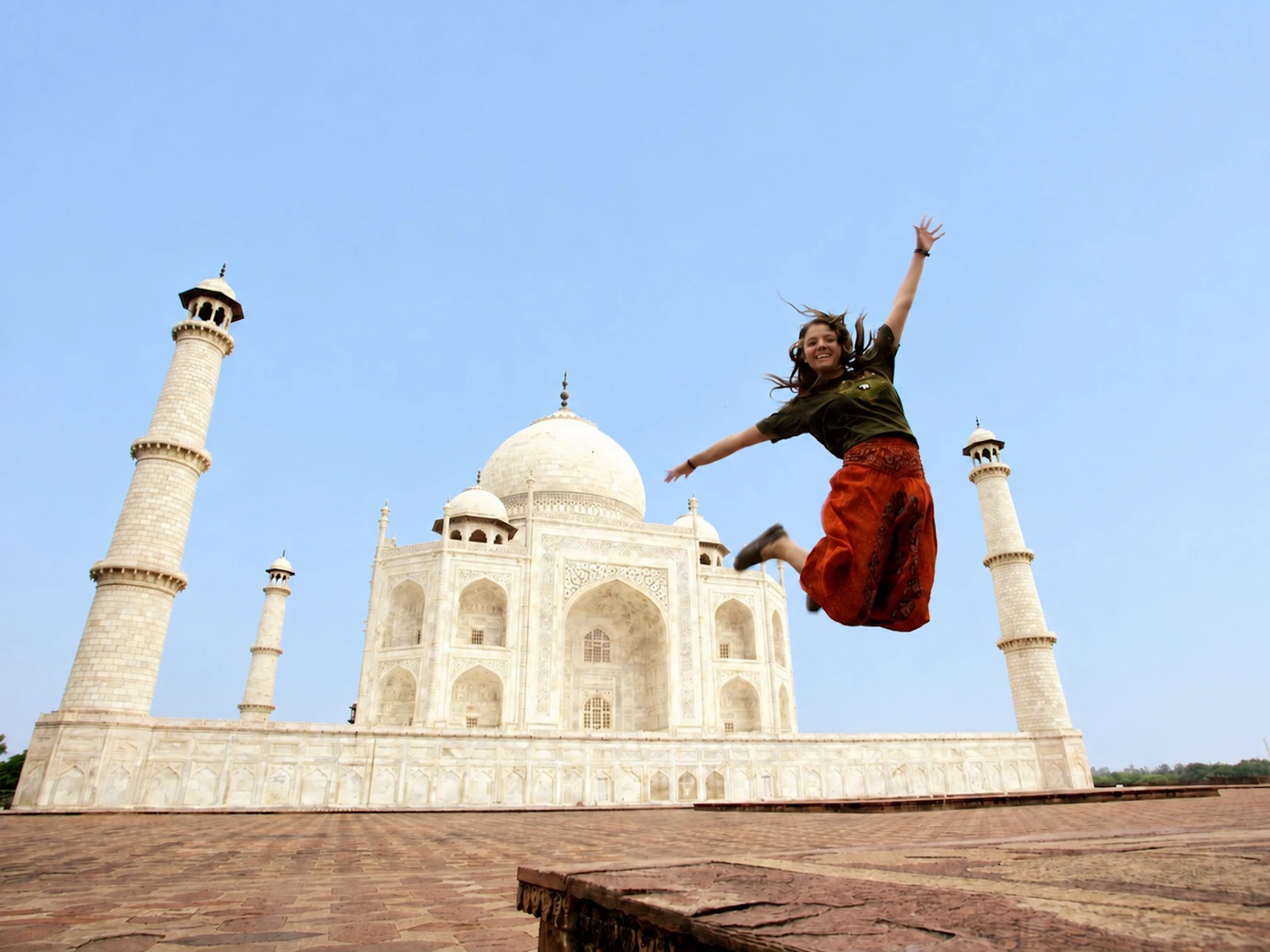 A student jumps in the air on the walkway in front of the Taj Mahal.