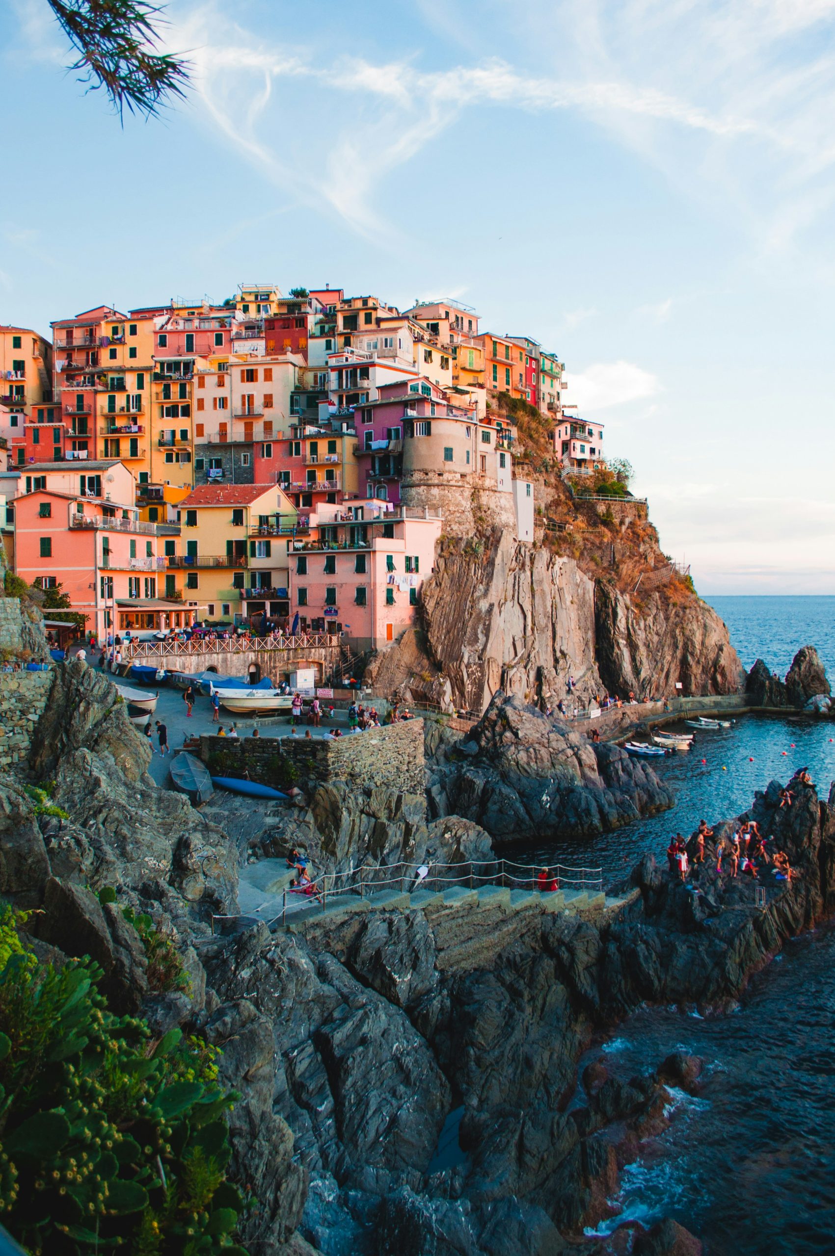 Picture of houses on a mountain on the left side and ocean on the right side in Manarola, Italy.