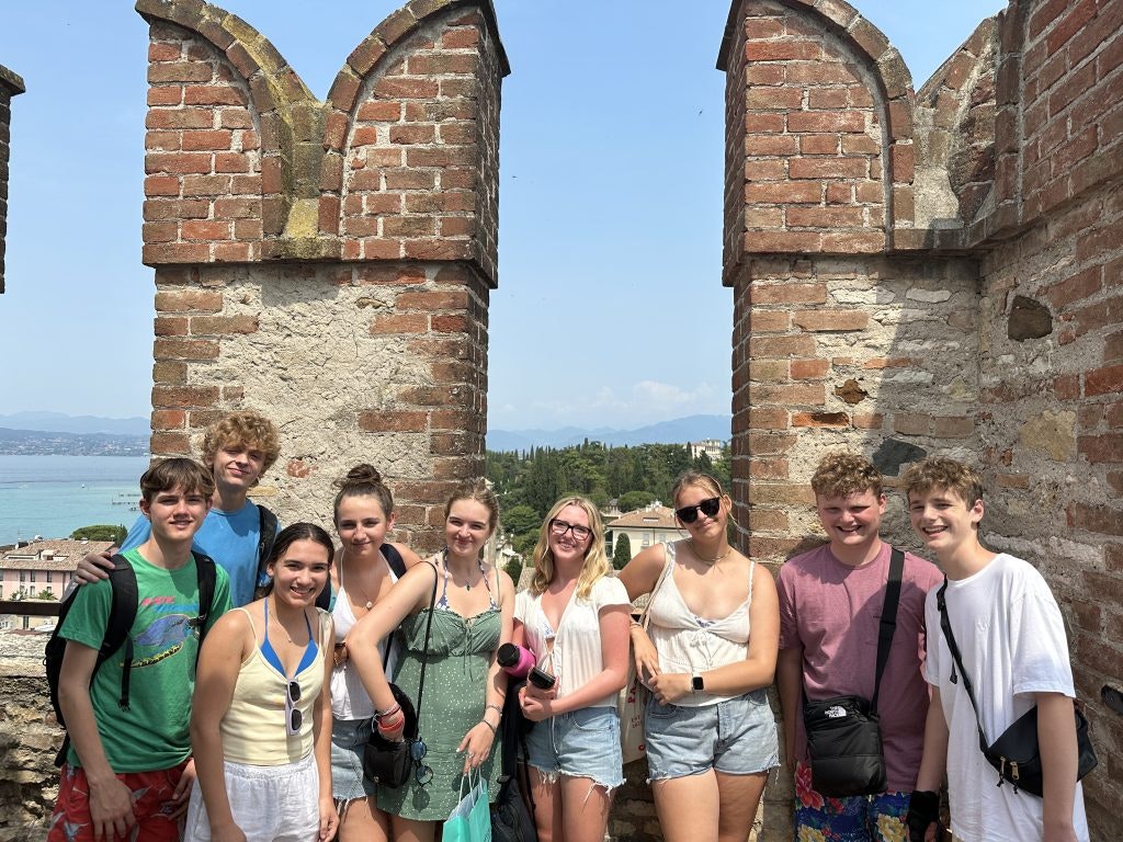 A group of students on the walls of a medieval castle at Lake Garda during an Italy teen tour.