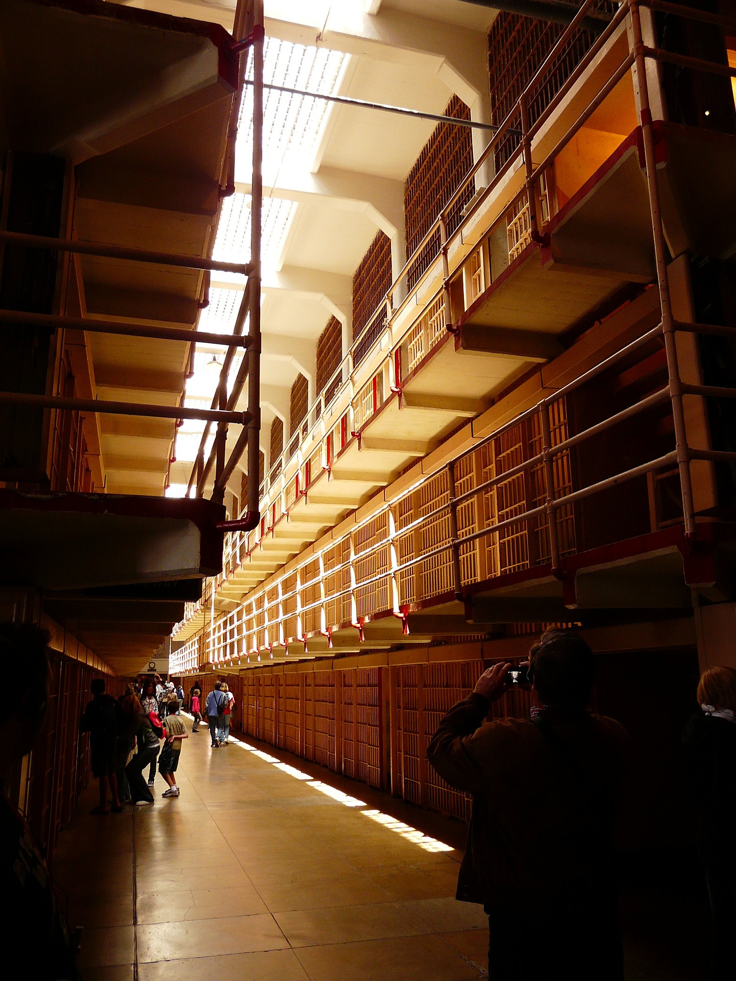 Visitors walk through a cellblock lined with tiered rows of cells at Alcatraz