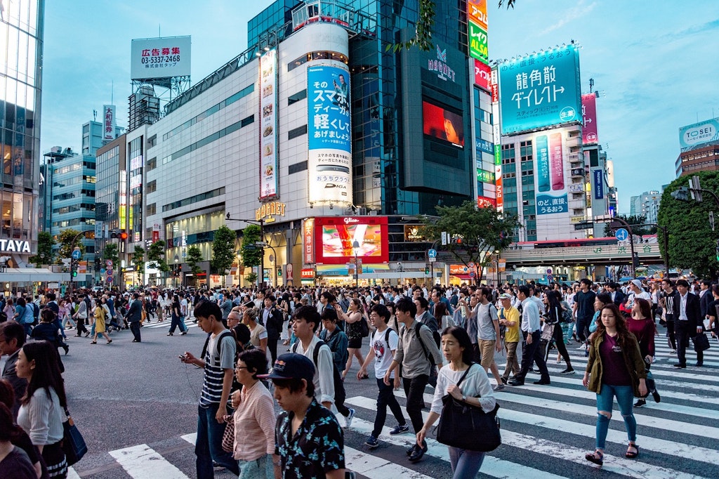 People walk across the Shibuya crossing.