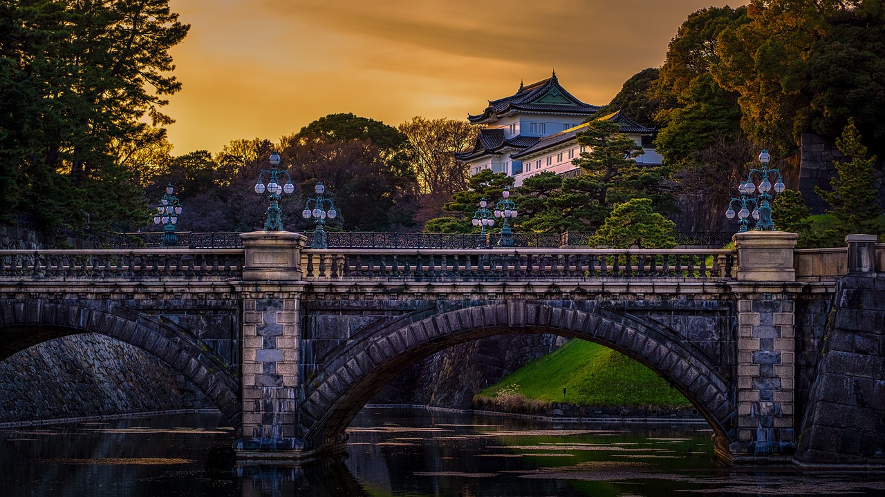 Stone bridge arches over a moat leading to the Imperial Palace at dusk