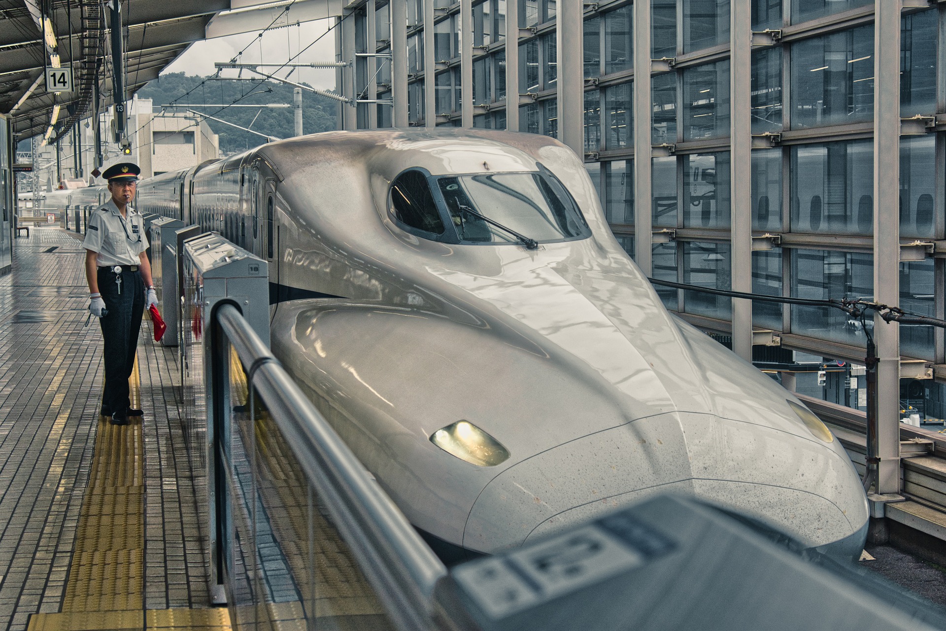 A shinkansen bullet train stopped at a station platform beside a conductor