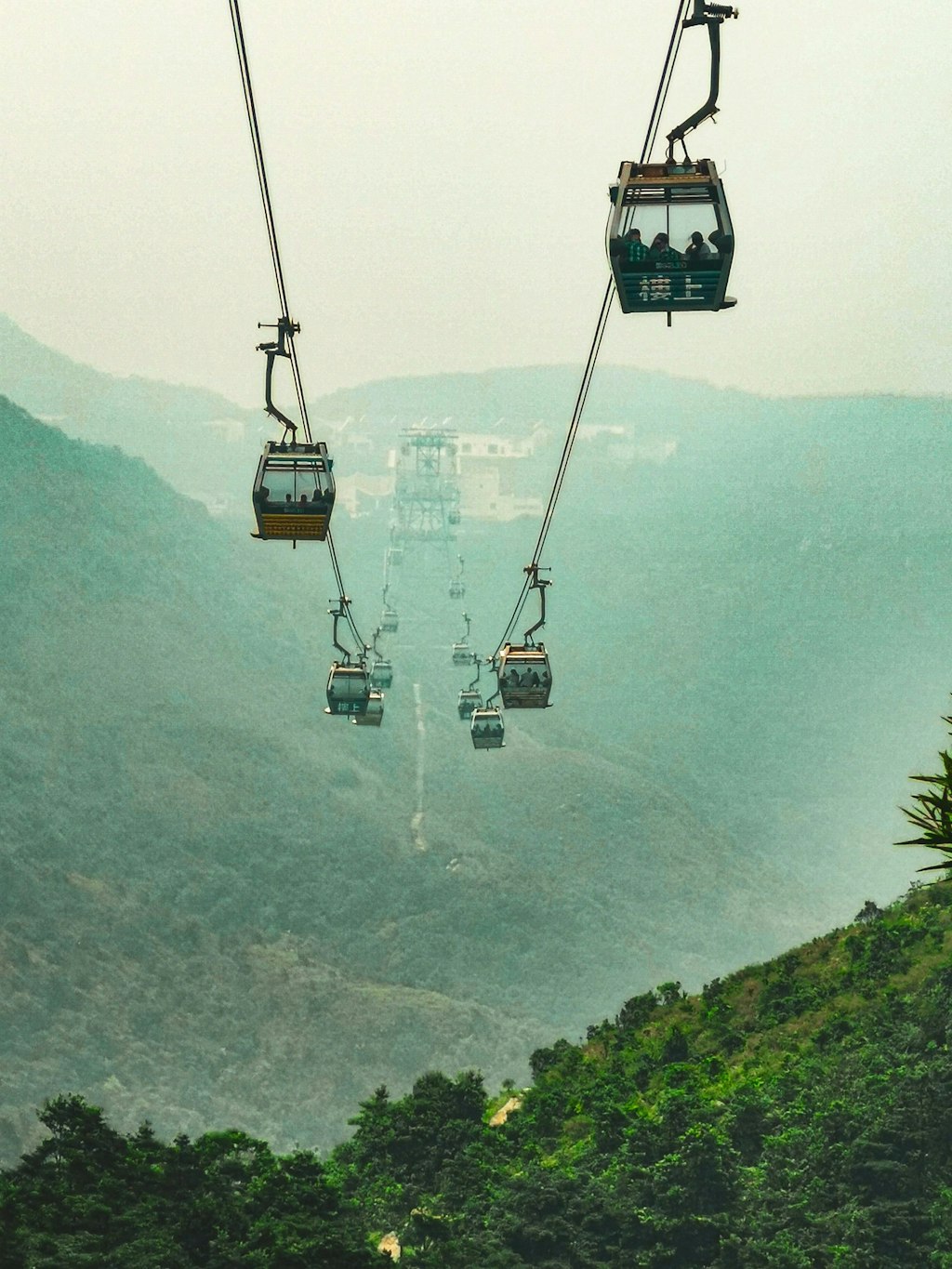 The Ngong Ping 360 Rescue Trail in Hong Kong featuring gondolas going up and down the green mountain.