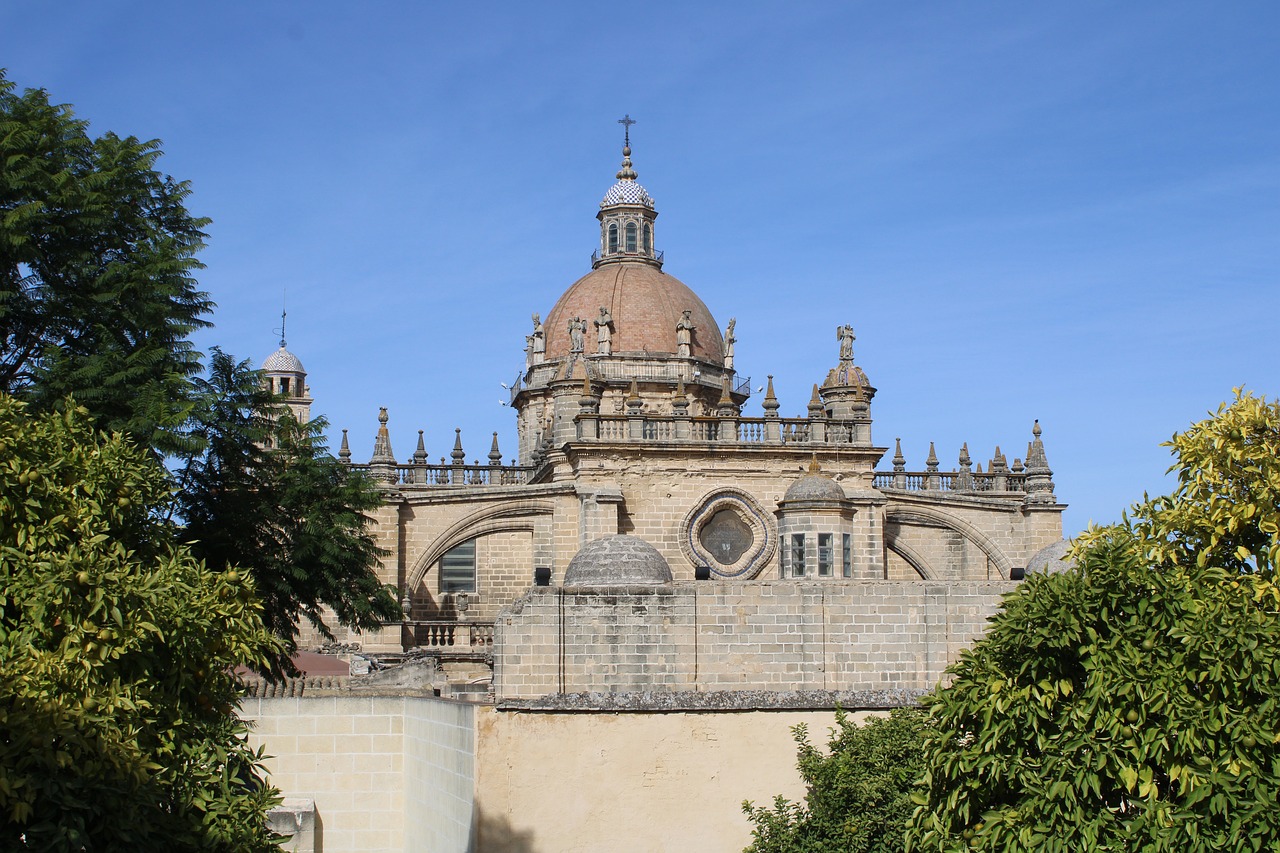 Domed cathedral tower rises above a stone wall lined with trees