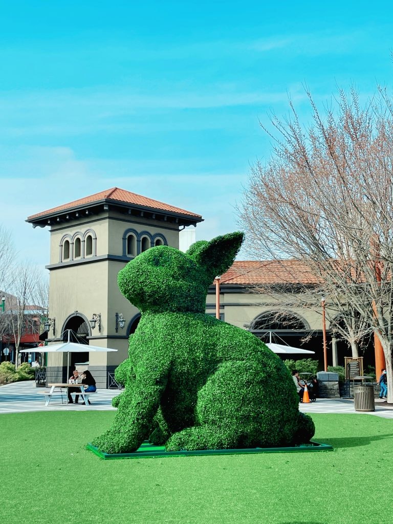 A green bush on the lawn was trimmed into the shape of a rabbit.