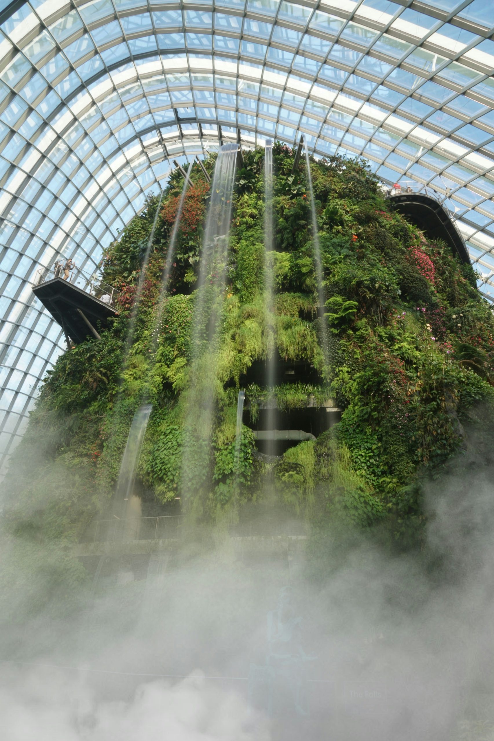 Waterfall cascading down a lush vertical garden inside the Cloud Forest Dome at Gardens by the Bay, Singapore.