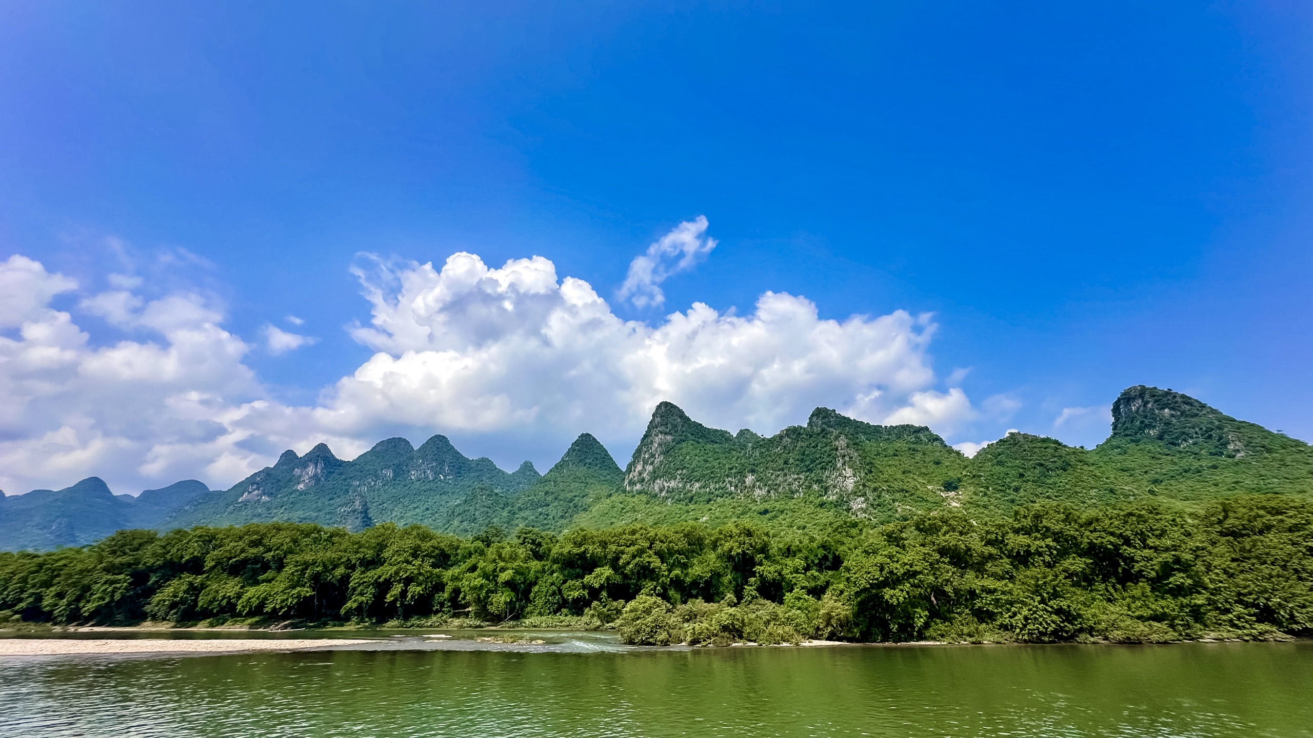 Limestone karst peaks and bamboo forest under a bright blue sky above the Li River near Guilin, China