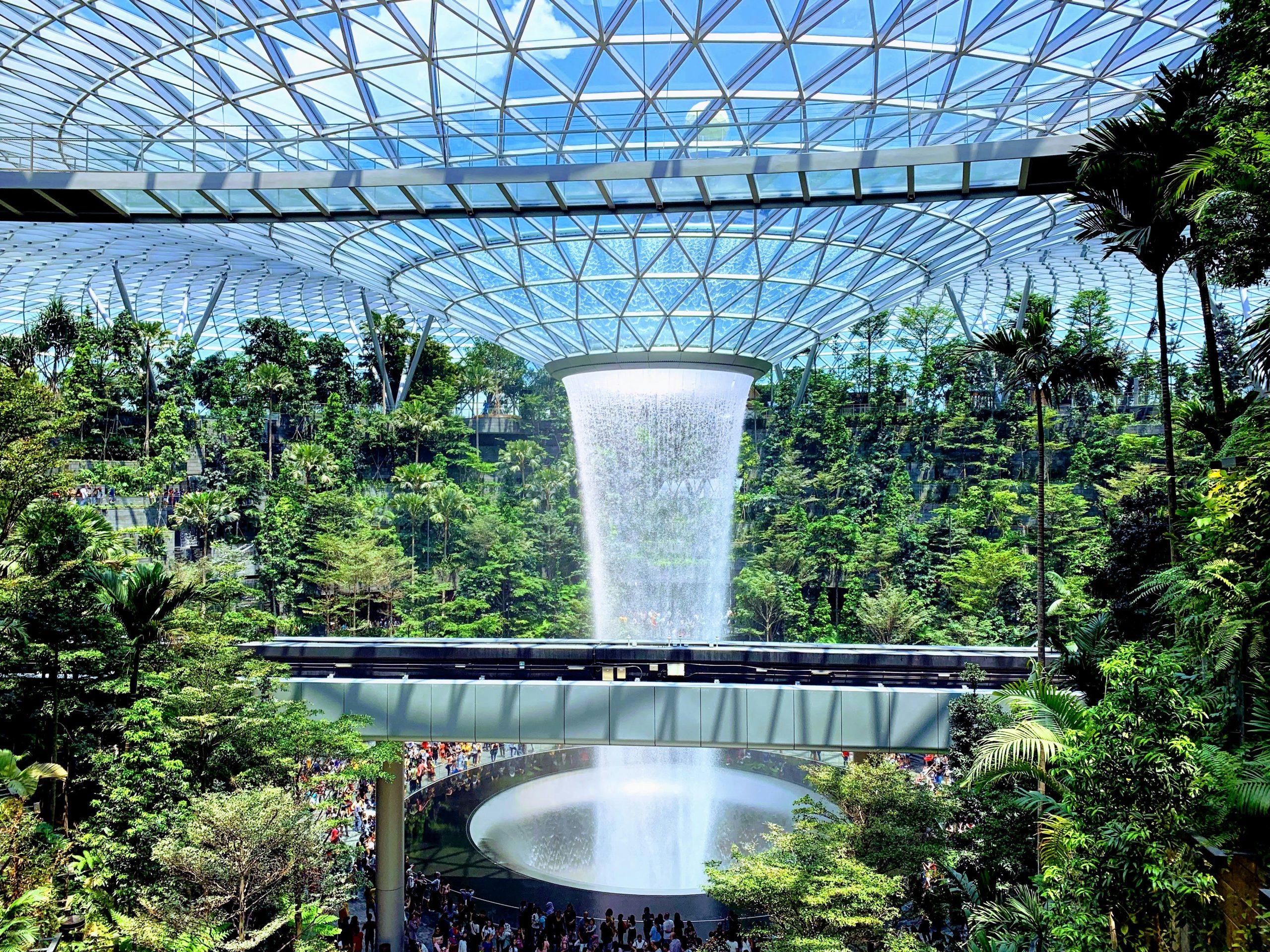 Rain Vortex waterfall inside Jewel Changi Airport surrounded by greenery under a glass dome.