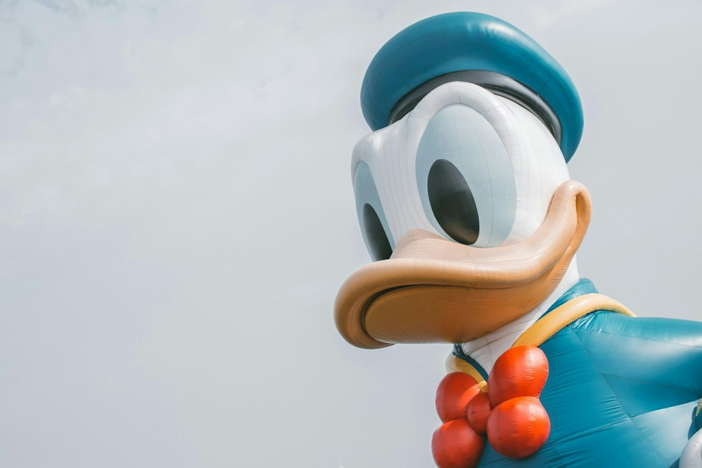 An inflatable Donald Duck stands against a grey sky.