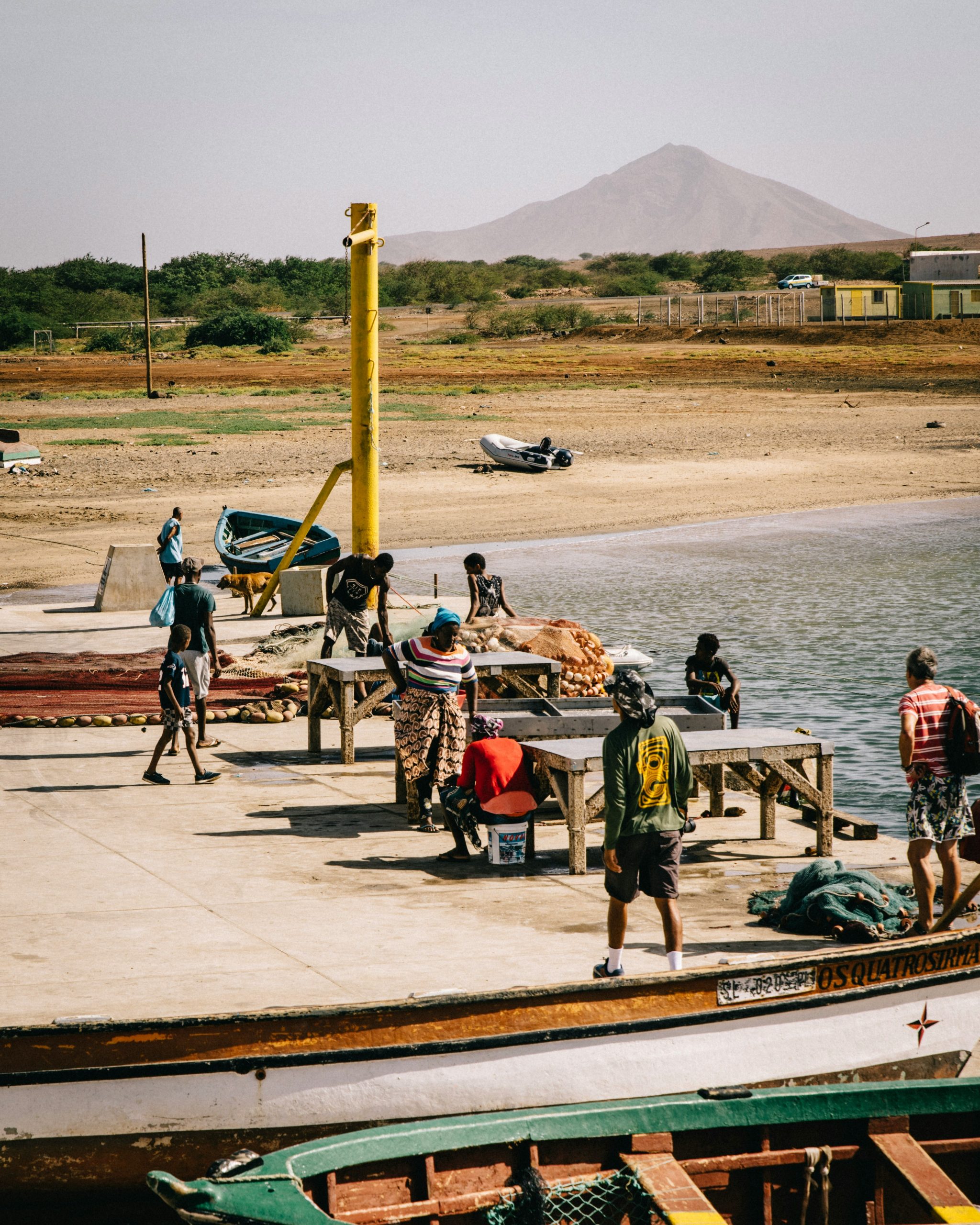 People working at a fishing dock with mountains in the background in Cape Verde