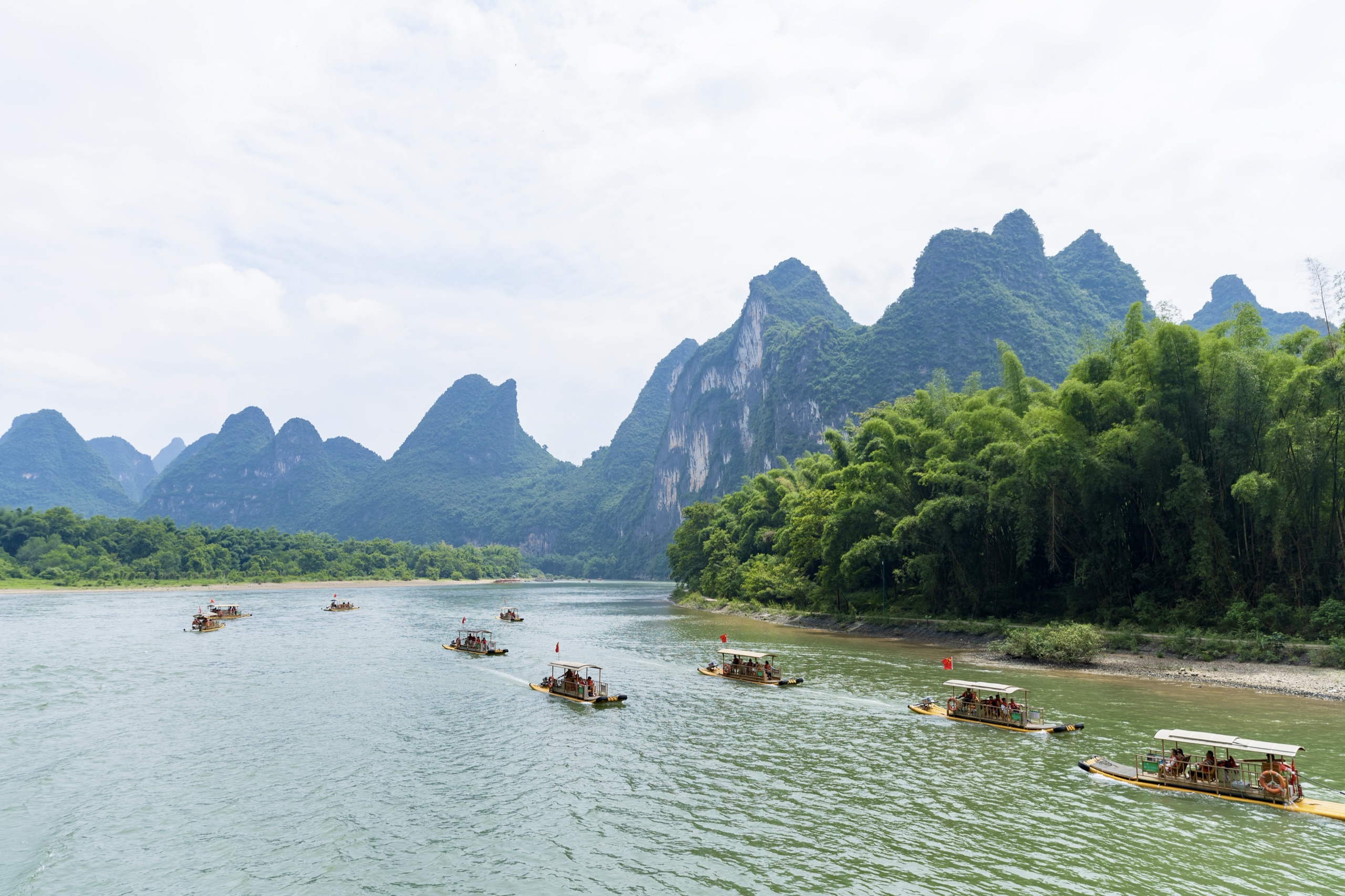Bamboo rafts drifting down the Li River past bamboo groves and limestone karst peaks near Yangshuo, China