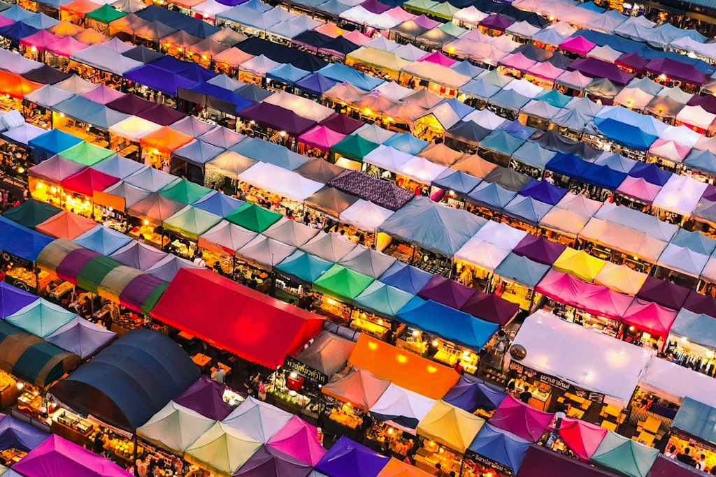 The picture shows a bird's-eye view of Chatuchak Weekend Market, filled with colorful stalls offering various goods.