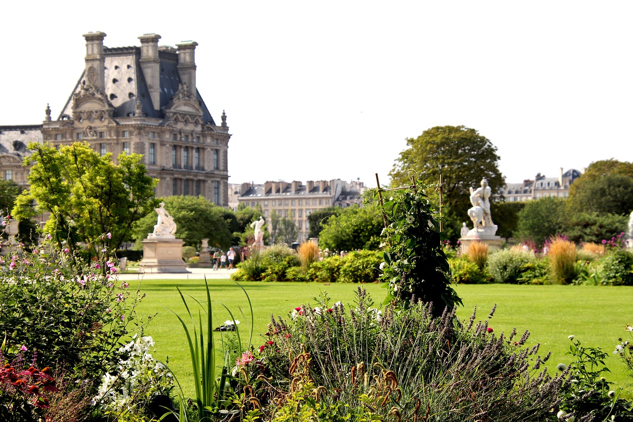 Statues and manicured lawns fill a Parisian garden in France with the Louvre's rooftop in the background