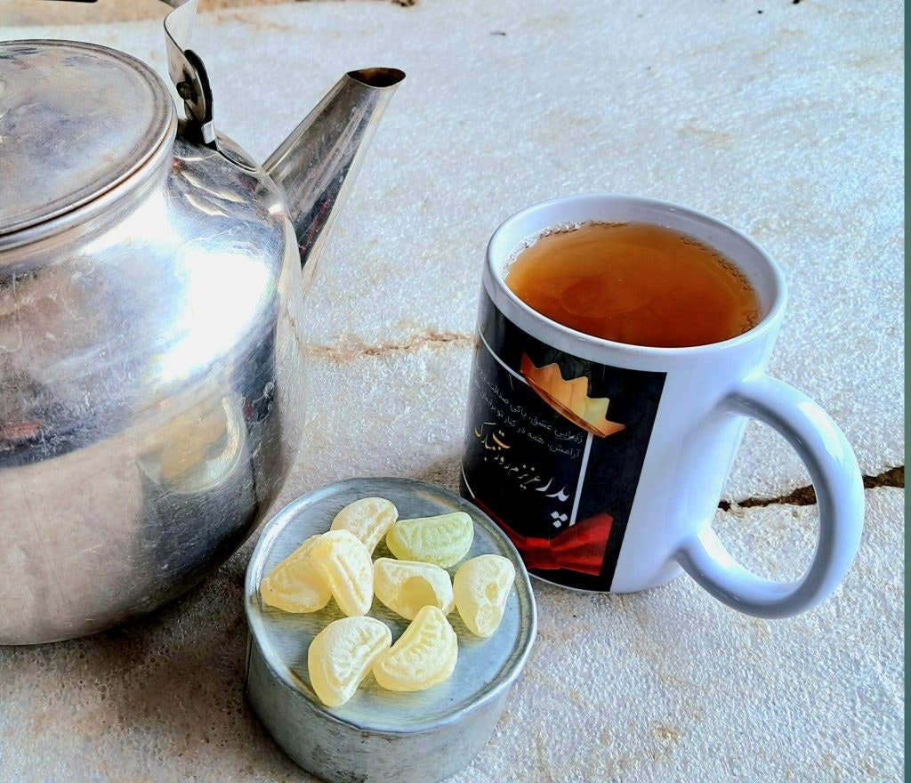 A teapot, a cup of tea, and lemon-flavored candies on a textured surface. fun facts about afghanistan