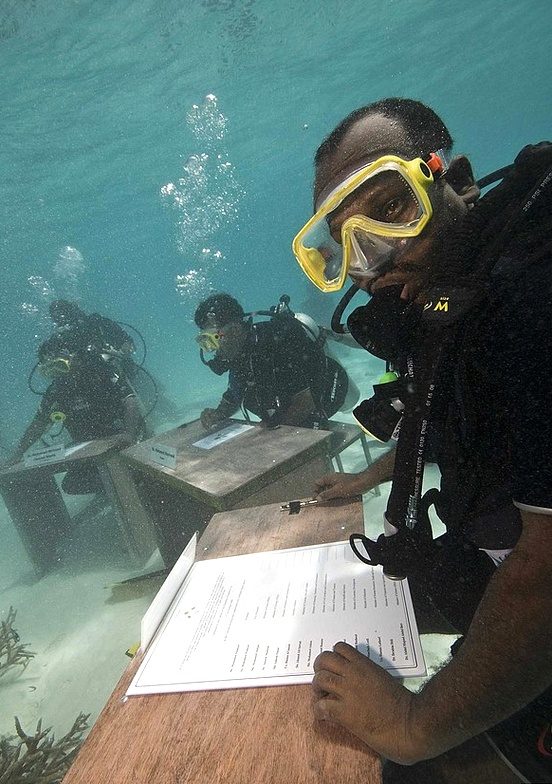 Maldivian government officials in scuba gear holding the world's first underwater cabinet meeting — a remarkable event tied to climate change awareness and fun facts about the Maldives and its environmental initiatives.