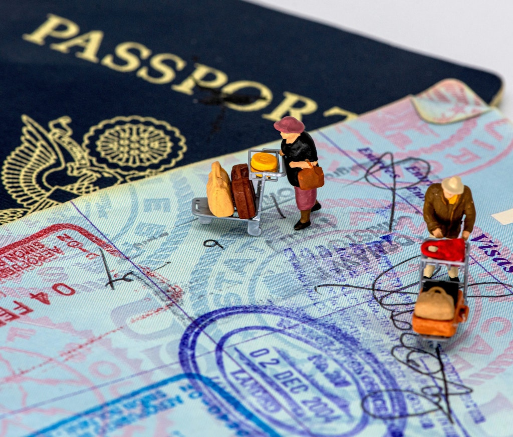 Close-up of passports and miniature travelers on visa pages, symbolizing the student travel visa process and documentation required for international study.