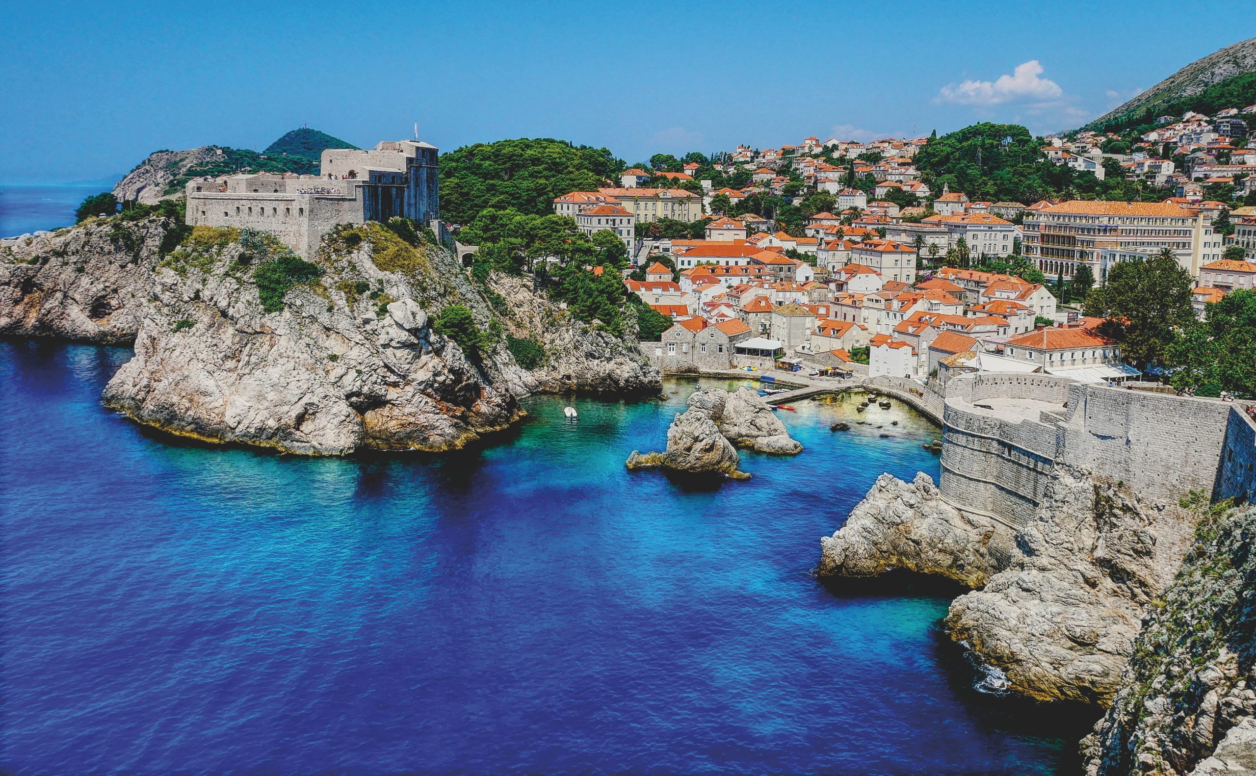 Rocky coastline and terracotta rooftops surround a walled coastal city in the Balkans