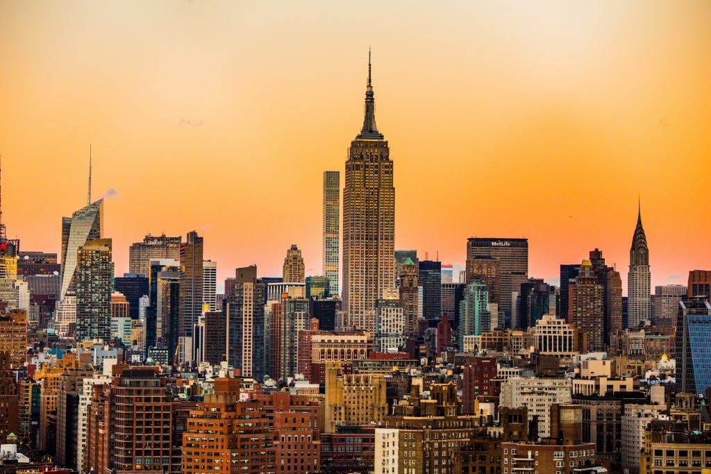 A cityscape of New York at golden hour with the Empire State Building visible in the center.