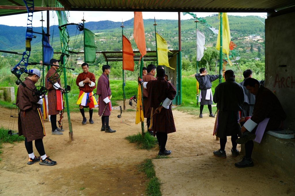 Men wearing the traditional clothes of Bhutan, standing ready to do archery