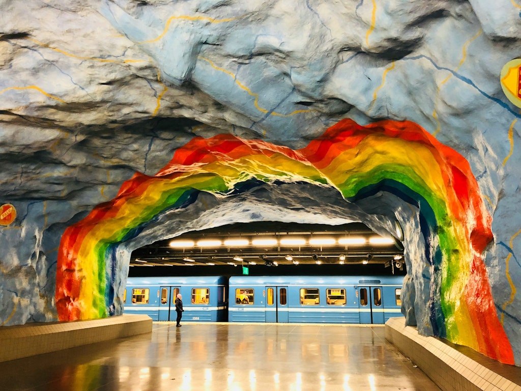 Artistic subway station in Copenhagen painted capturing a passing train. The artwork is painted in various colors featuring a rainbow.