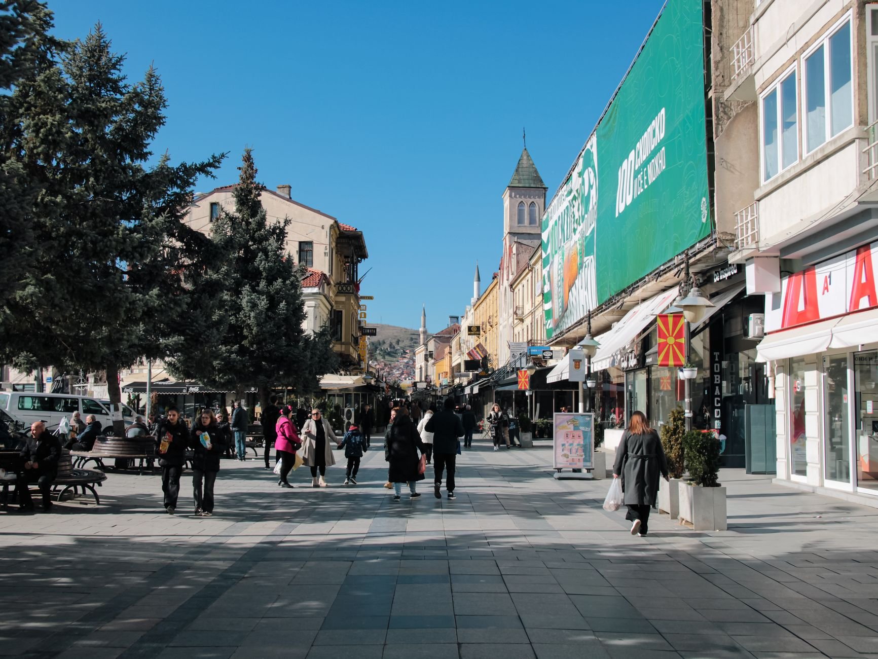 A busy pedestrian street lined with shops and cafes in a historic town center.