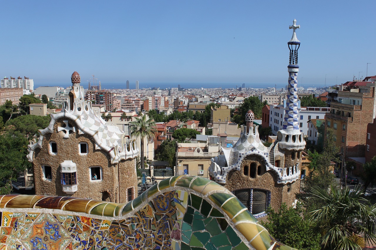 Mosaic-tiled terrace and Gaudí's gatehouses overlook Barcelona's skyline at Park Güell