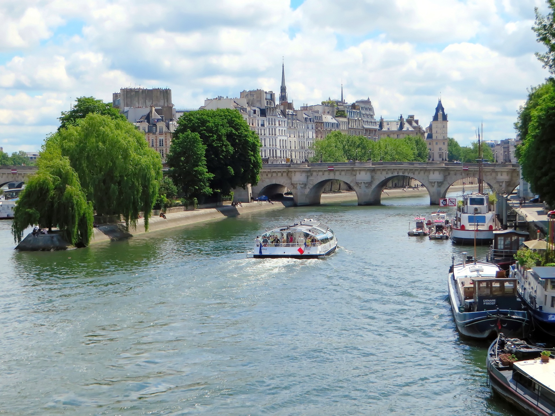 A tour boat cruises the Seine River past a stone bridge in Paris