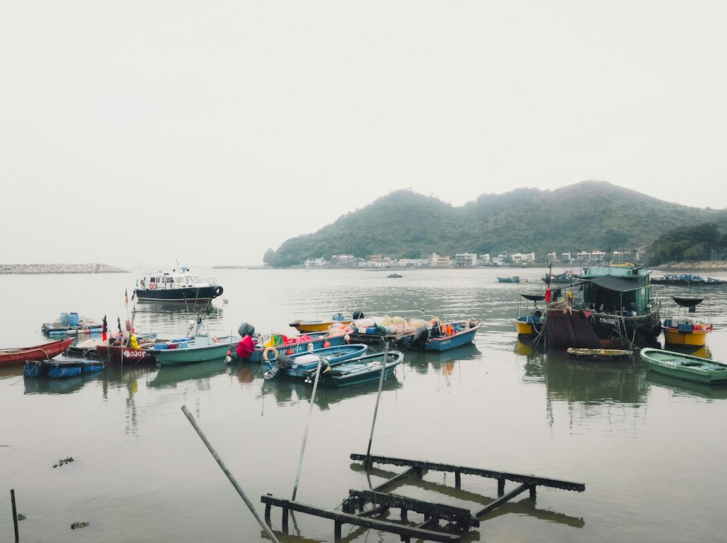 The picture shows one of Hong Kong's more remote areas, where boats rest gently on the water with mountains rising in the background.