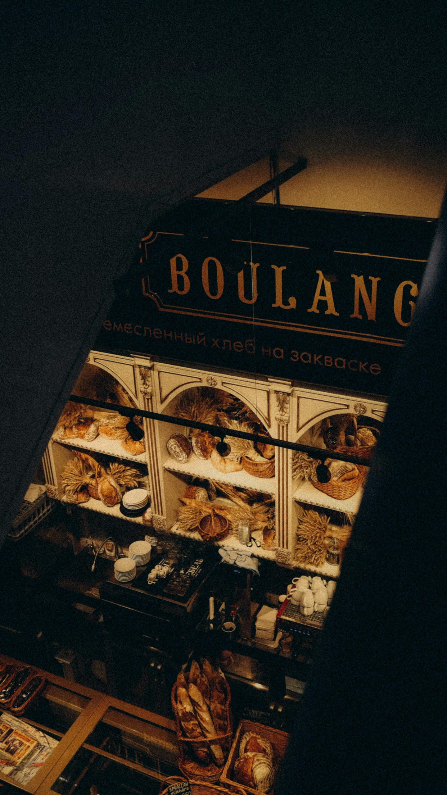 A bakery window displays loaves and baskets of bread beneath a lit Boulangerie sign