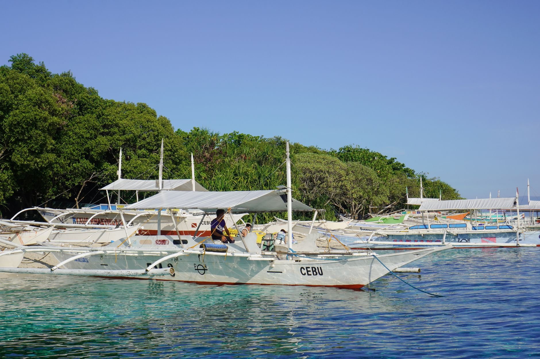 Outrigger boats resting in clear, shallow turquoise water near a shoreline.