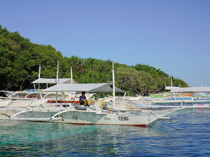 Outrigger boats resting in clear, shallow turquoise water near a shoreline.