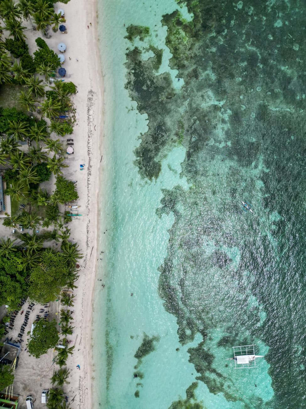 A curved white sand beach meeting turquoise water, seen from above.